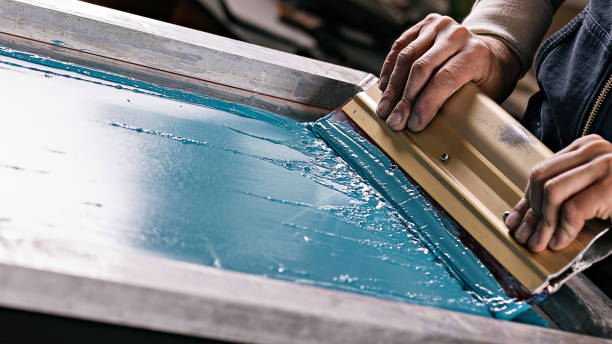Pulling a screen print by hand on the press in the Hatrick Sportswear shop in Norton, Massachusetts
